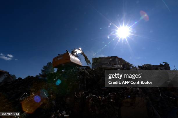 Picture taken on August 23, 2017 in Amatrice shows a machine on rubble, a year after a deadly earthquake left nearly 300 people dead and destroyed...