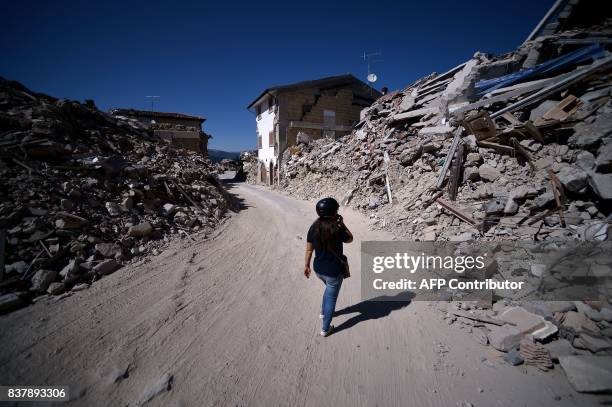 Woman walks in the remains of Amatrice on August 23, 2017 a year after a deadly earthquake left nearly 300 people dead and destroyed the small town....