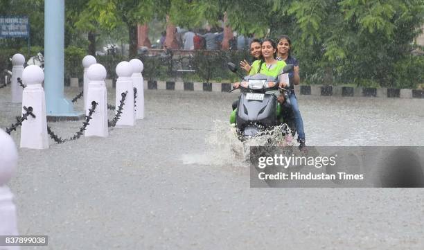 Girls ride scooty through waterlogged campus during heavy rains, at Rajasthan University, on August 23, 2017 in Jaipur, India.