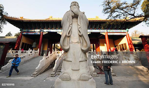 Visitors walk past a statue on the grounds of the Confucius Temple, named for Chinese philosopher Confucius, best known for promoting filial piety in...