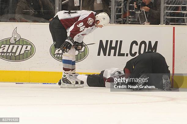Adam Foote of the Colorado Avalanche is attended by Head Athletic Trainer Matthew Sokolowski as he lays on the ice after being checked into the...
