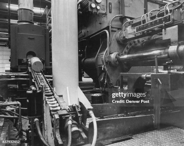 Here's the heart of Dow's magnesium extrusion press. At upper left a magnesium alloy ingot two feet long and heated to 900 degrees slides down roller...