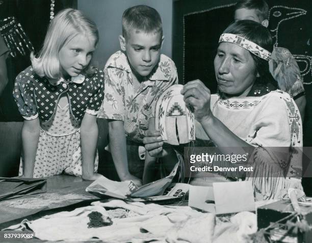 Shhh! Indians At Work -- Watching intently as Mrs. Alice Blackhorse stitches beadwork on a colorful Indian moccasin are Theresa Quinlan of 3358...