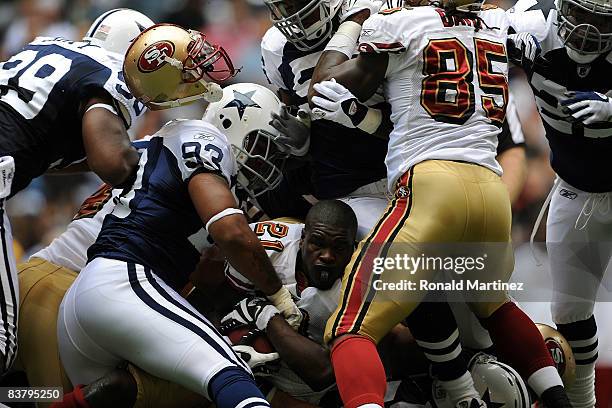 Running back Frank Gore of the San Francisco 49ers loses his helmet while tackled by Anthony Spencer of the Dallas Cowboys at Texas Stadium on...