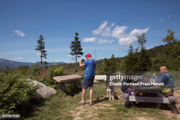 Tom Henaghen takes a photo of the view from the scenic lookout point at Stop 6 in the Katahdin Woods and Waters National Monument. Henaghen and his...