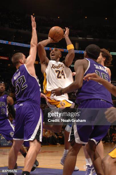 Kobe Bryant of the Los Angeles Lakers goes up for a shot between Brad Miller and John Salmons of the Sacramento Kings at Staples Center on November...
