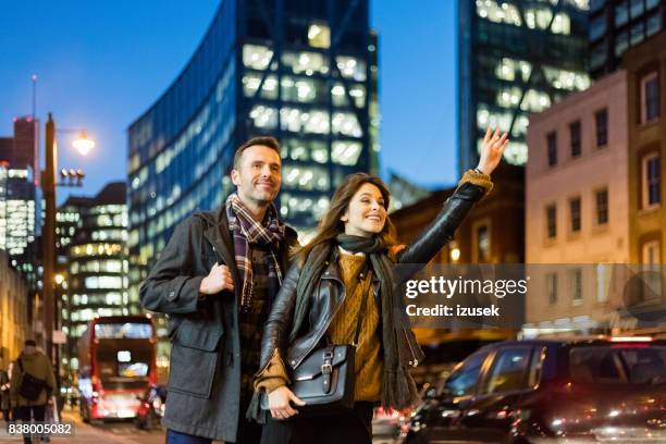 couple on street hailing for a cab - london taxi stock pictures, royalty-free photos & images