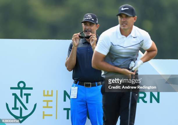 Claude Harmon III, golf caoch, watches Brooks Koepka of the USA during practice for The Northern Trust at Glen Oaks Club on August 23, 2017 in...