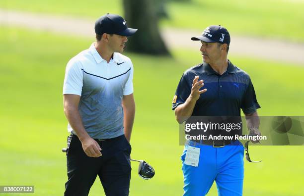 Brooks Koepka of the USA walks with his coach Claude Harmon III during practice for The Northern Trust at Glen Oaks Club on August 23, 2017 in...