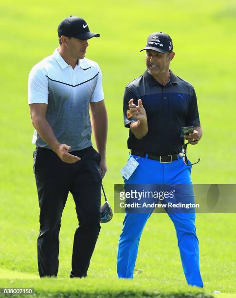 Brooks Koepka of the USA walks with his coach Claude Harmon III during practice for The Northern Trust at Glen Oaks Club on August 23, 2017 in...