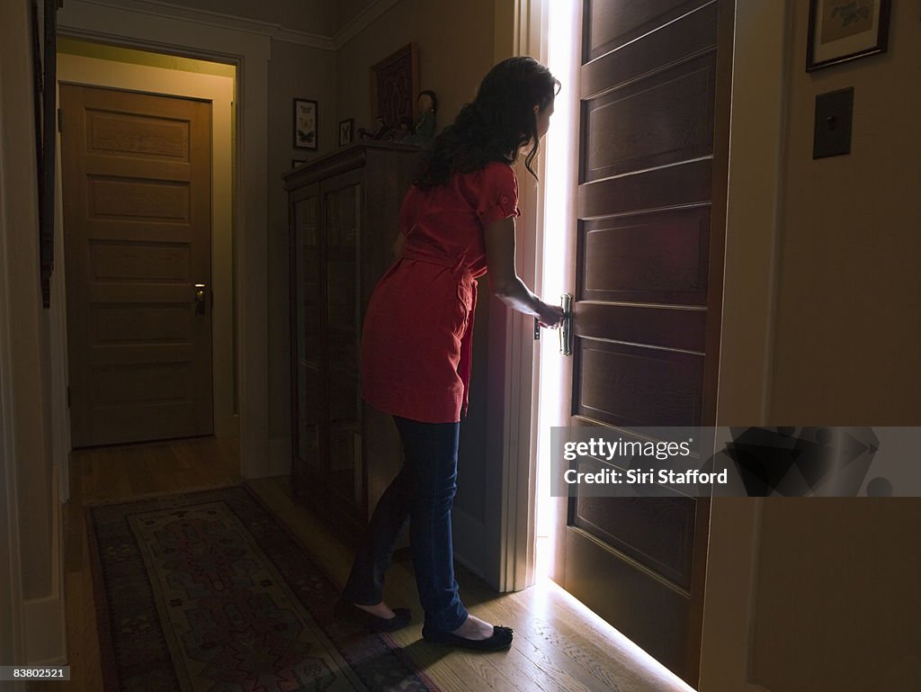 Woman opening bedroom door with light coming out