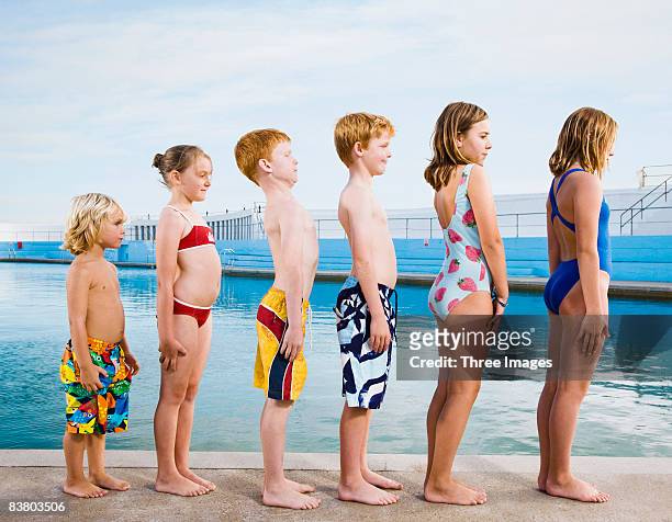line of children standing to attention by pool - tween girl swimsuit stock-fotos und bilder