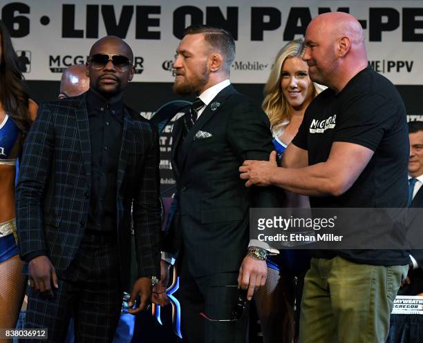 Boxer Floyd Mayweather Jr. Poses as UFC lightweight champion Conor McGregor is pulled back by UFC President Dana White during a news conference at...