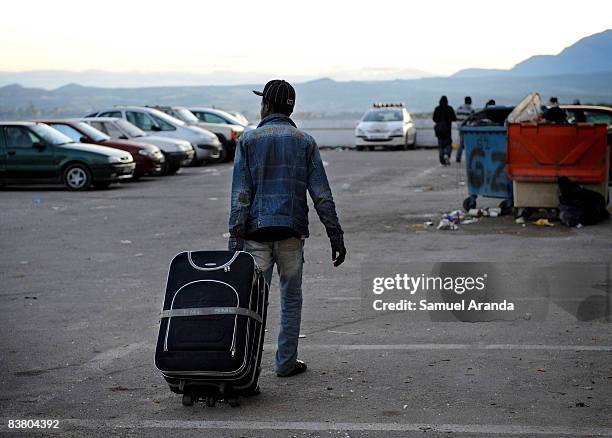 An illigal immigrant rolls his belongings behind him as he arrives at an aid center November 20, 2008 in Jaen, Spain. Jobs such as the yearly olive...