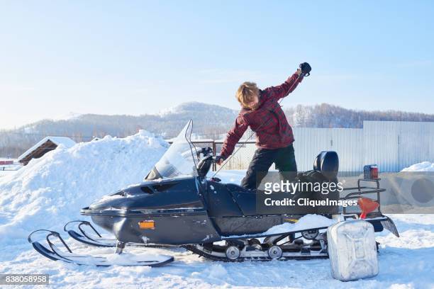 man starting snowmobile - cliqueimages stock-fotos und bilder