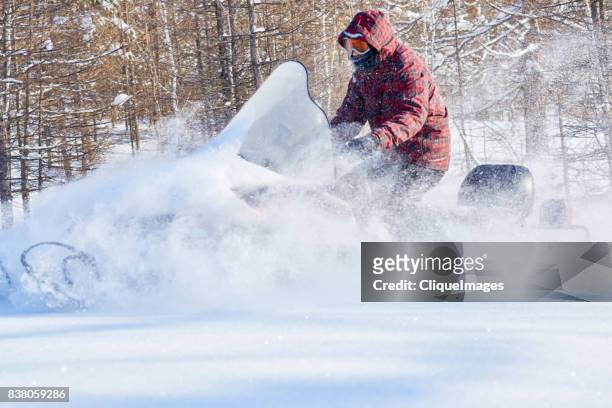 man taking extreme snowmobile ride - cliqueimages stock-fotos und bilder
