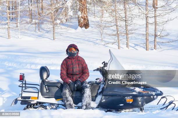 snowmobile driver resting after ride - cliqueimages stock-fotos und bilder