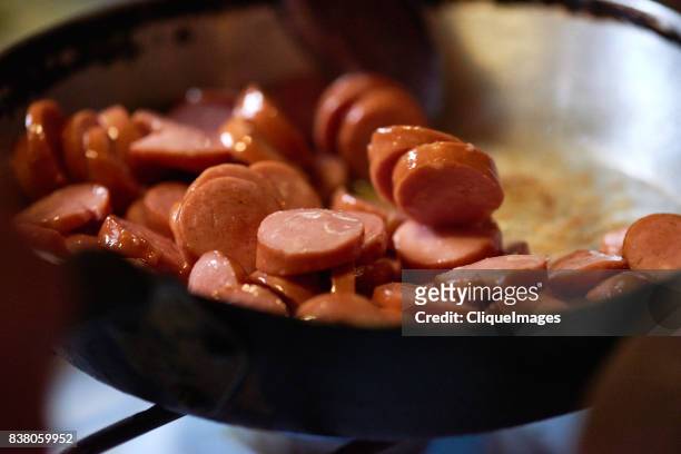 delicious fried sausage in pan - cliqueimages stock-fotos und bilder