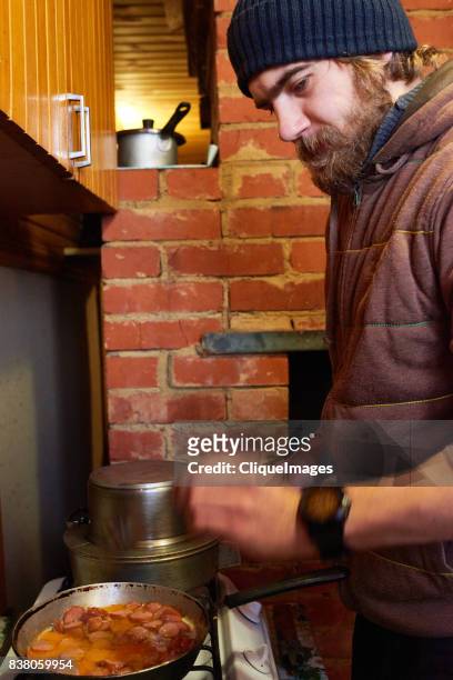 bearded man frying sausages - cliqueimages stock pictures, royalty-free photos & images