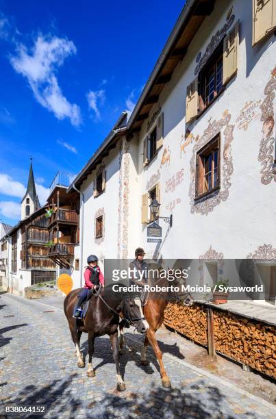 woman and child ride horses in the old town, guarda, switzerland - paesaggi - fotografias e filmes do acervo