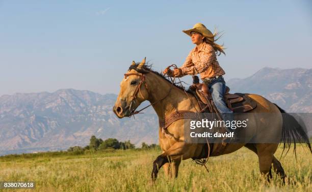 junge frau auf einem pferd durch die prärie - cowgirl stock-fotos und bilder