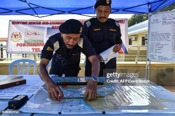 Members of the Malaysian Maritime Enforcement Agency mark on a map for the search and rescue operation for the missing sailors from the USS John S....