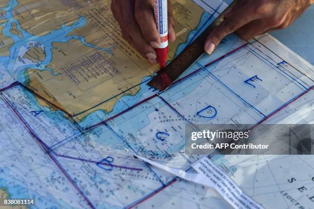Member of the Malaysian Maritime Enforcement Agency marks on a map for the search and rescue operation for the missing sailors from the USS John S....