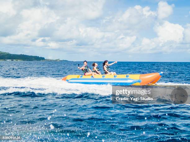 three women riding a banana boat in guam - guam capital stock pictures, royalty-free photos & images