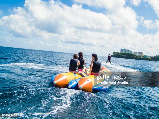 three women riding a banana boat in guam - guam capital stock pictures, royalty-free photos & images