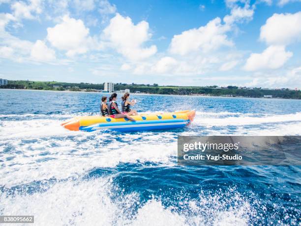 three women riding a banana boat in guam - guam capital stock pictures, royalty-free photos & images