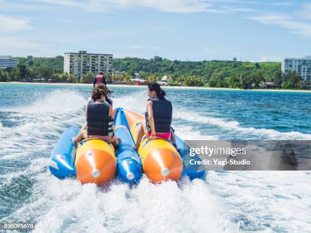 three women riding a banana boat in guam - guam capital stock pictures, royalty-free photos & images