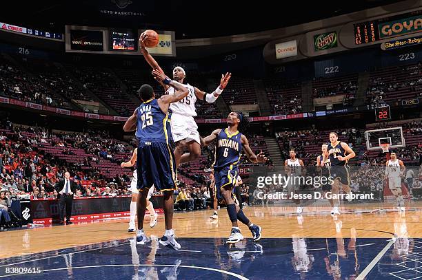 Keyon Dooling of the New Jersey Nets lays the ball up over Brandon Rush and Marquis Daniels of the Indiana Pacers during the game on November 12,...