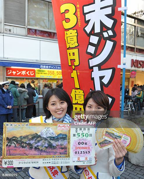 Campaign girls Eri Yasui and Emi Saido display lottery tickets and a giant mock ticket for the 300 million yen Year-End Jumbo Lottery while people...