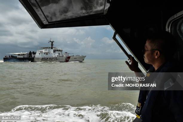 Member of the Malaysian Maritime Enforcement Agency looks out during the rescue operation for the missing sailors from the USS John S. McCain off the...
