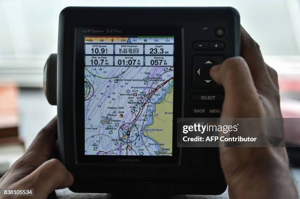 Member of the Malaysian Maritime Enforcement Agency checks the GPS navigation system during the rescue operation for the missing sailors from the USS...