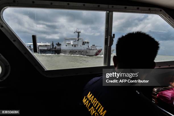 Member of the Malaysian Maritime Enforcement Agency looks out of an observation window during the rescue operation for the missing sailors from the...