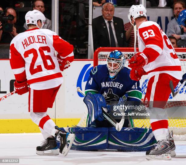 Jiri Hudler and Johan Franzen of the Detroit Red Wings look on as Curtis Sanford of the Vancouver Canucks makes a save during their game at General...
