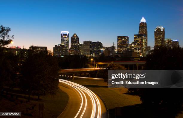 Charlotte North Carolina skyline at night with traffic blurs and twilight.