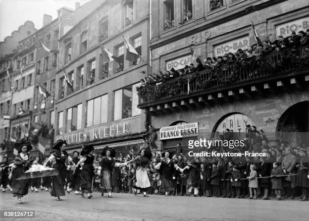Un joyeux cortège d'Alsaciennes en costume dans les rues de la ville en fête, à Strasbourg, France le 24 novembre 1946.