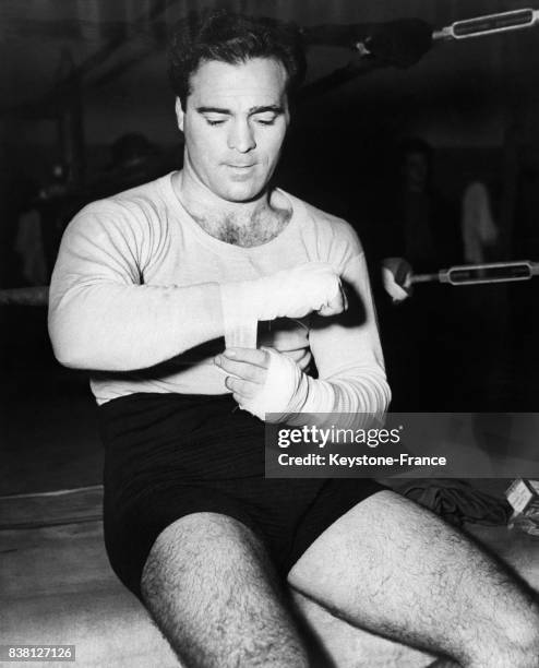 Le boxeur Marcel Cerdan s'entoure les mains de badelettes avant de mettre ses gants et de débuter son entraînement au gymnase CYO à New York City,...