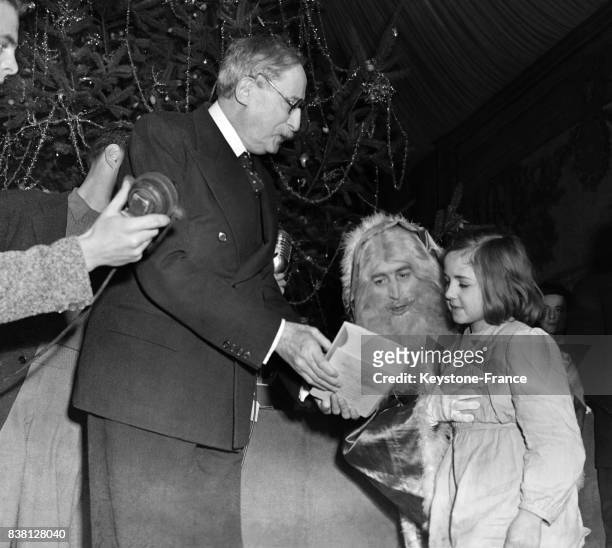 Le président Blum, assisté du Père Noël, distribue les cadeaux devant l'arbre de Noël, à Paris, France en décembre 1946.