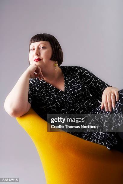 woman sitting in chair, hand under chin - personal strength stock pictures, royalty-free photos & images