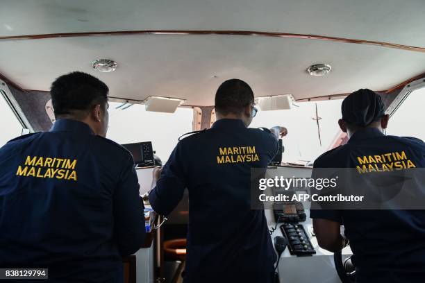 Malaysian Maritime Enforcement Agency officer points to an object during the rescue operation for the missing sailors from the USS John S. McCain off...