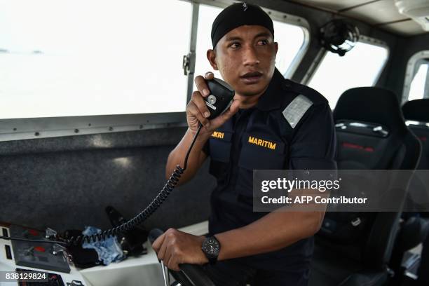 Member of the Malaysian Maritime Enforcement Agency talks on the radio during the rescue operation for the missing sailors from the USS John S....