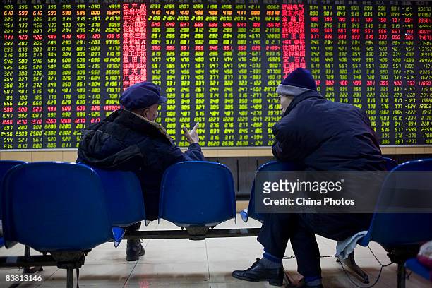Two investors chat as they view stock index at a securities company on November 25, 2008 in Changchun of Jilin Province, China. Chinese stocks...