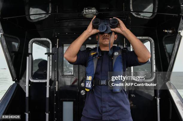 Member of the Malaysian Maritime Enforcement Agency officer uses a pair of binoculars to scan the sea during the rescue operation for the missing...