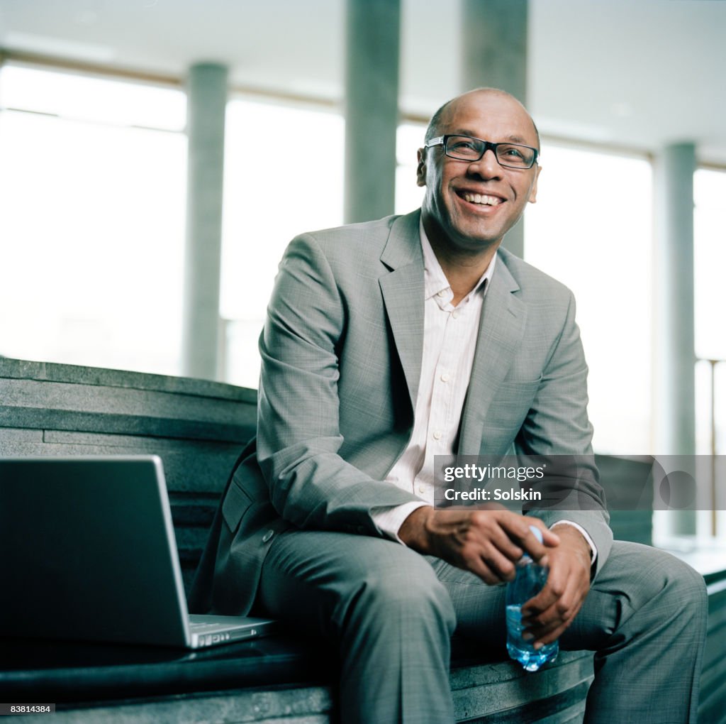 Businessman sitting in stairs in office hallway