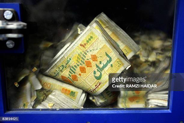 Lebanese lira bills are damaged in a special machine at Lebanon's Central Bank in Beirut on November 24, 2008. Lebanon for now has managed to steer...