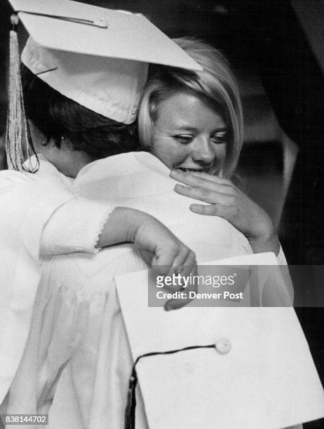 Sandi Young, 1988 S. Zenobia St., right, hugs her friend Becky Frazer, 2325 Stuart St., following graduation exercises of Abraham Lincoln High School...