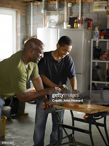 father demonstrating carpentry skills to son - influence stockfoto's en -beelden